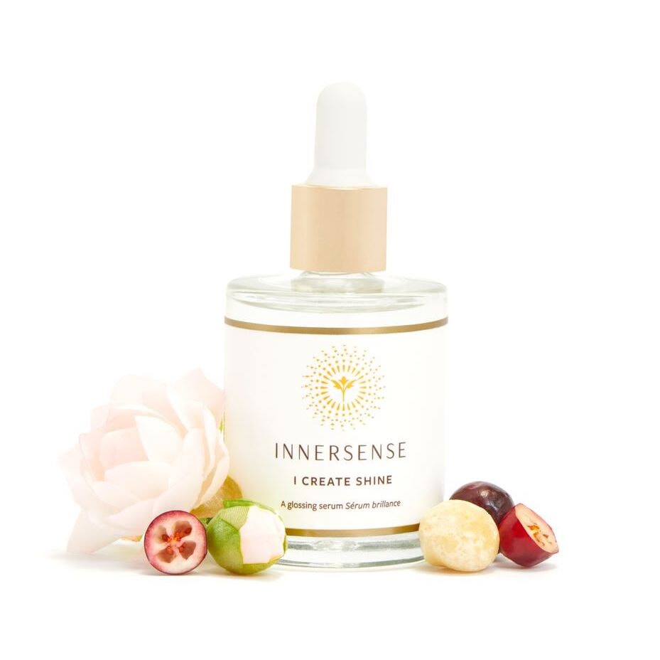 Innersense I Create Shine Pipettenflasche steht vor weißem Hintergrund dekoriert mit Blütenblättern und Beeren.