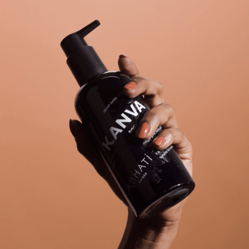 Eine Hand hält Abhati Suisse Kanva Bodylotion schwarze Pumpflasche.