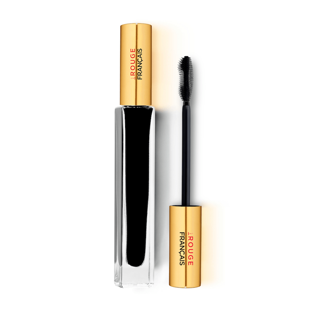 Glasflasche der Mascara Le Noir Cassiopée No 410 steht neben einer Silikonwimpernbürste vor weißem Hintergrund.