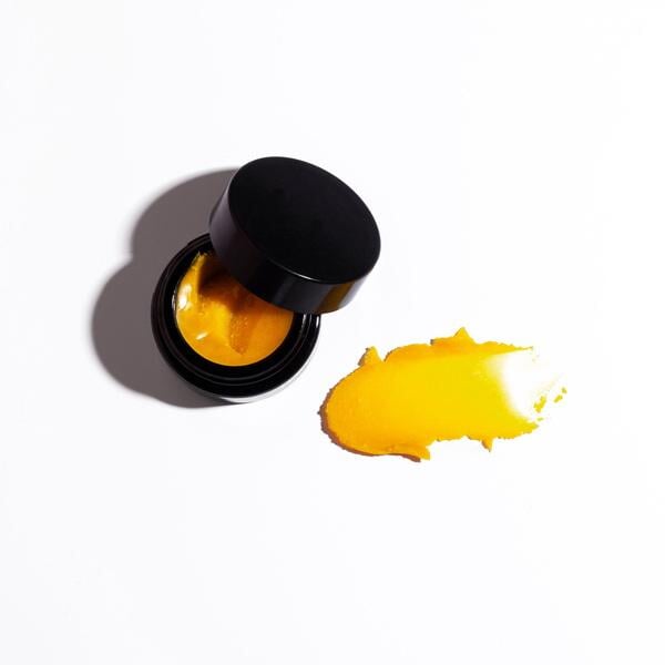 Offener, schwarzer Tiegel der Henné Lip Mask mit angelehntem Deckel vor weißem Hintergrund mit Farb- und Texturbeispiel.