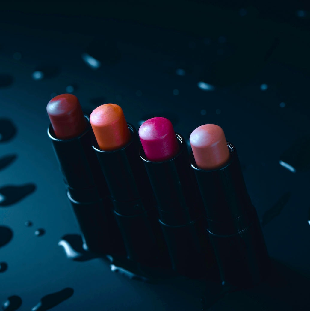 4 verschiedene, offene Lippenstifte von Henné Organics stehen auf schwarzem Untergrund. North Glow