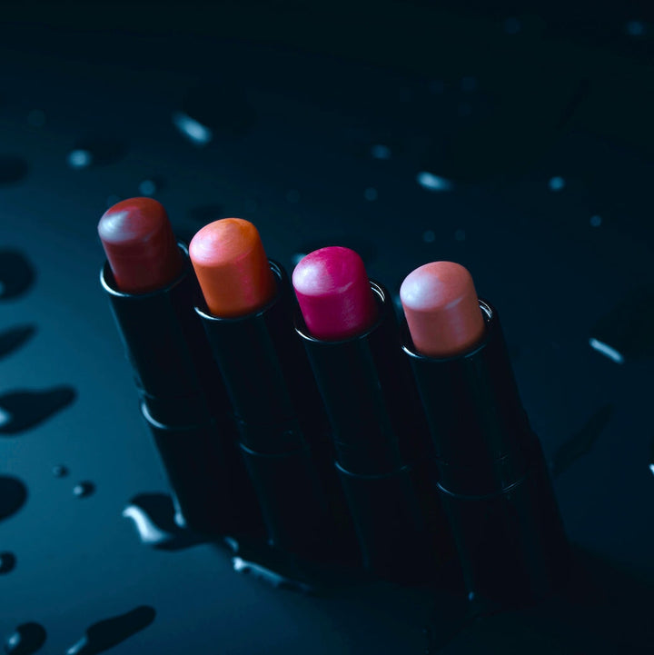 4 verschiedene, offene Lippenstifte von Henné Organics stehen auf schwarzem Untergrund.