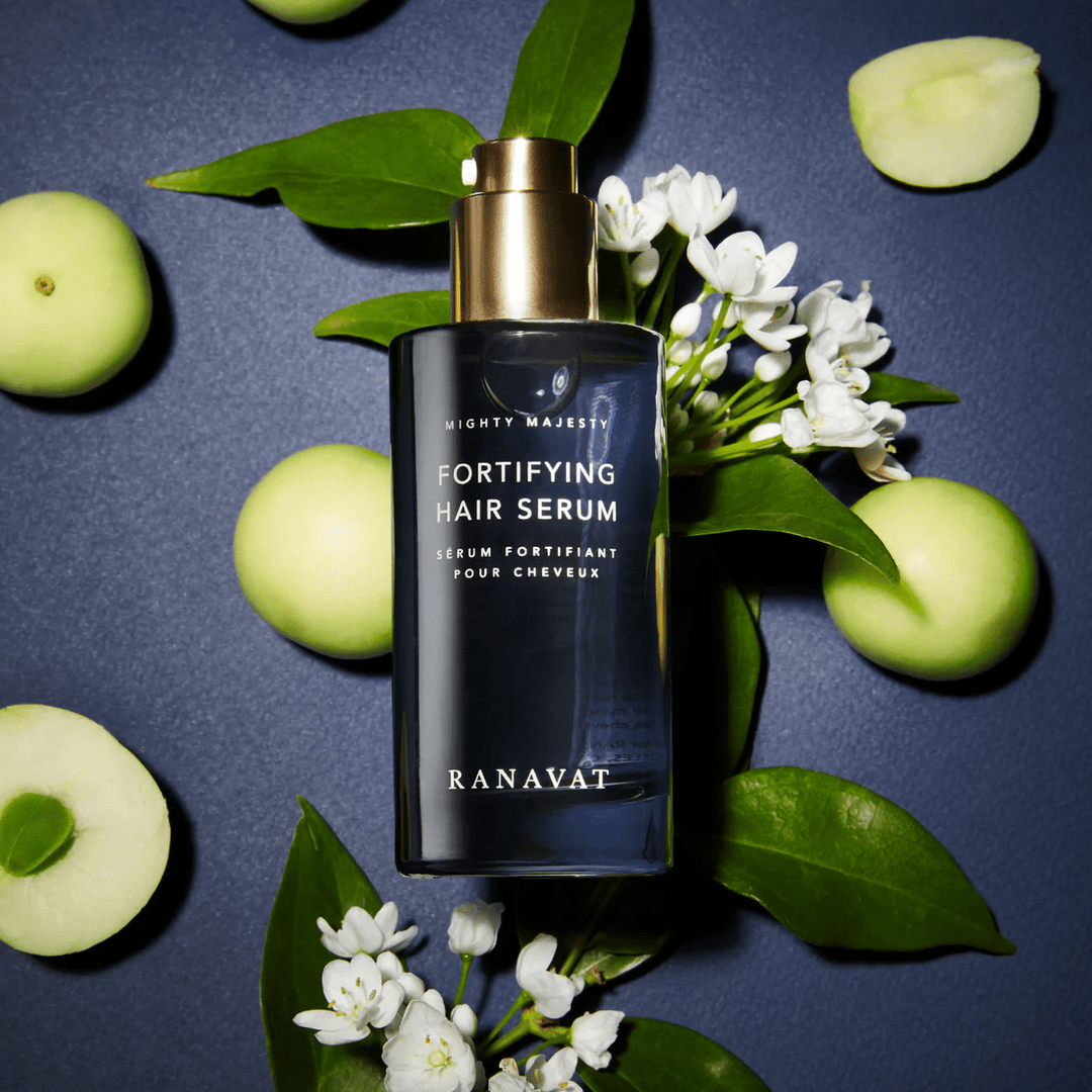 Ranavat Mighty Majesty Haarserum auf blauem Hintergrund mit Blättern, weißen Blüten und grünen Äpfeln
