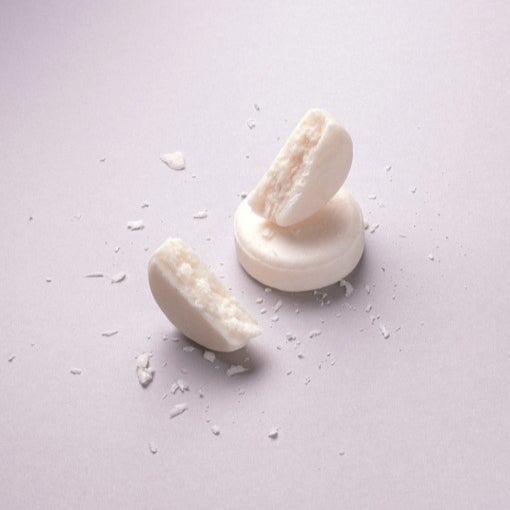 Abhati Suiss Nanda festes Shampoo Stück  liegt zerbrochen auf hellem Untergrund.