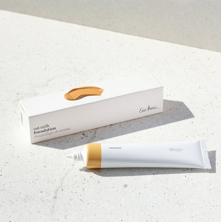 Offene Tube der Oat Milk Foundation Farbe Caramel mit Verpackung und Farb- und Texturbeispiel auf der Verpackung.