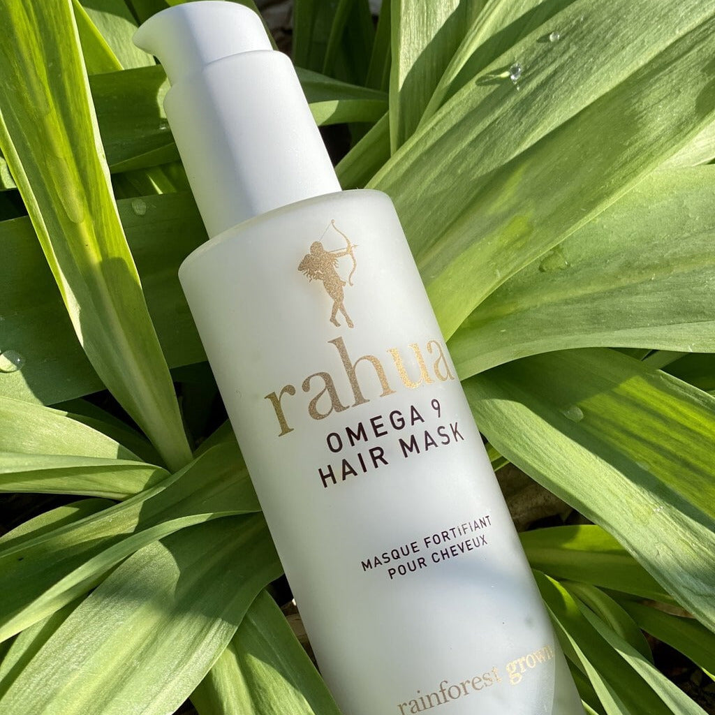 Rahua Omega 9 Hair Mask Flasche liegt in einer Pflanze.