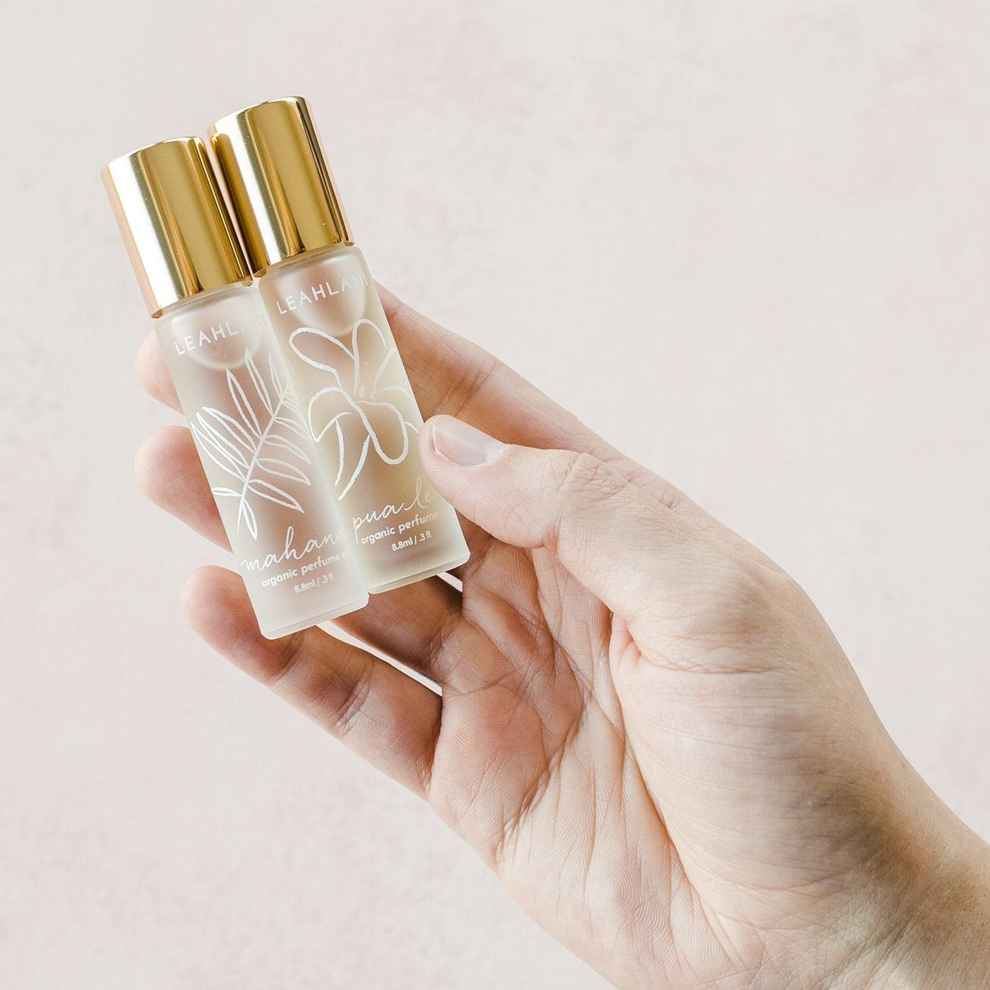 Leahlani Mahana Perfume Oil und Pua Lei wird von weiblicher Hand vor hellem Hintergrund gehalten