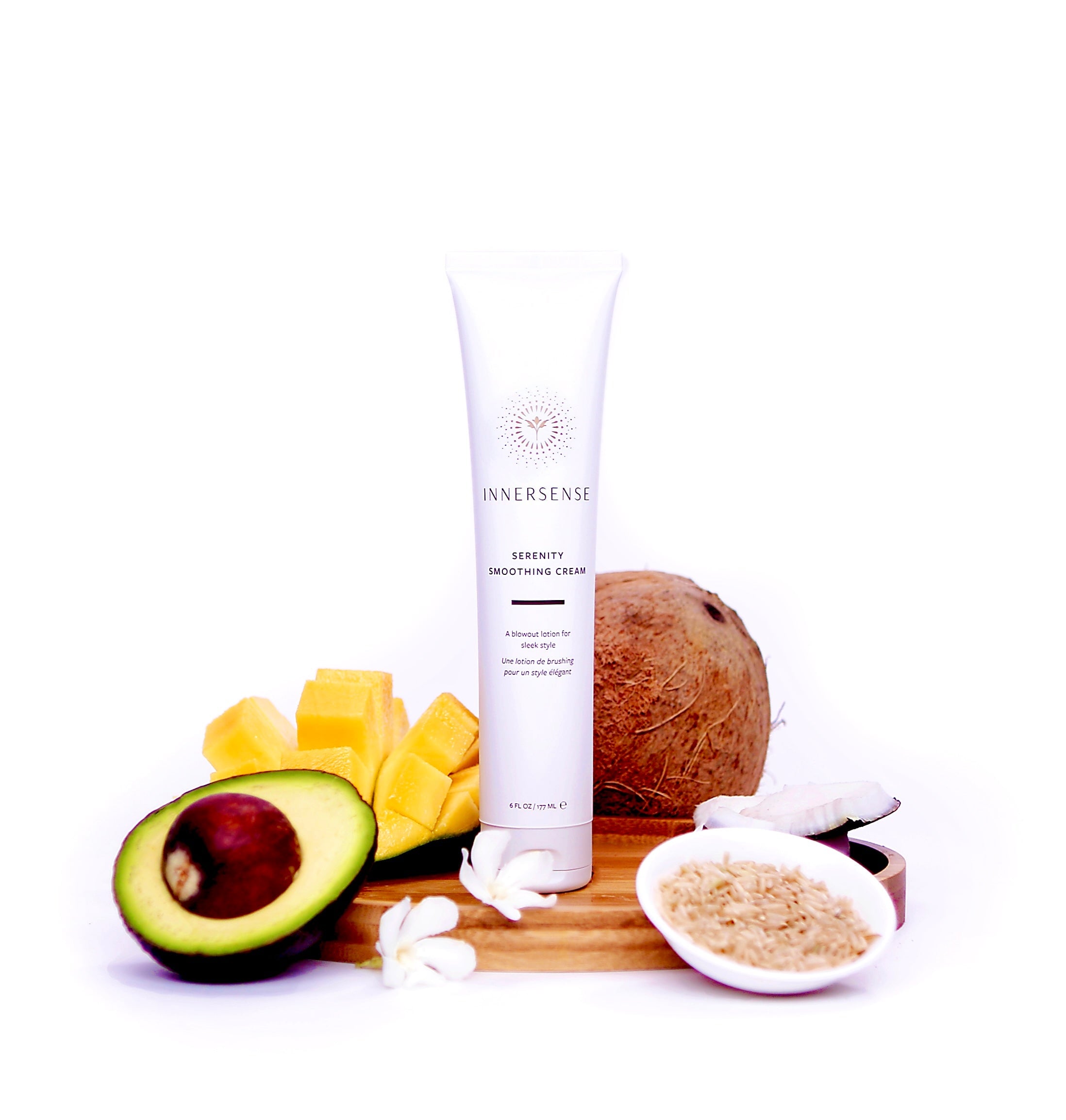 Innersense Serenity Smoothing Cream Tube auf einem Holttablett mit aufgschnittener Avocado und Mango, sowie eine Kokosnuss und Reiskörner in einer Schale.