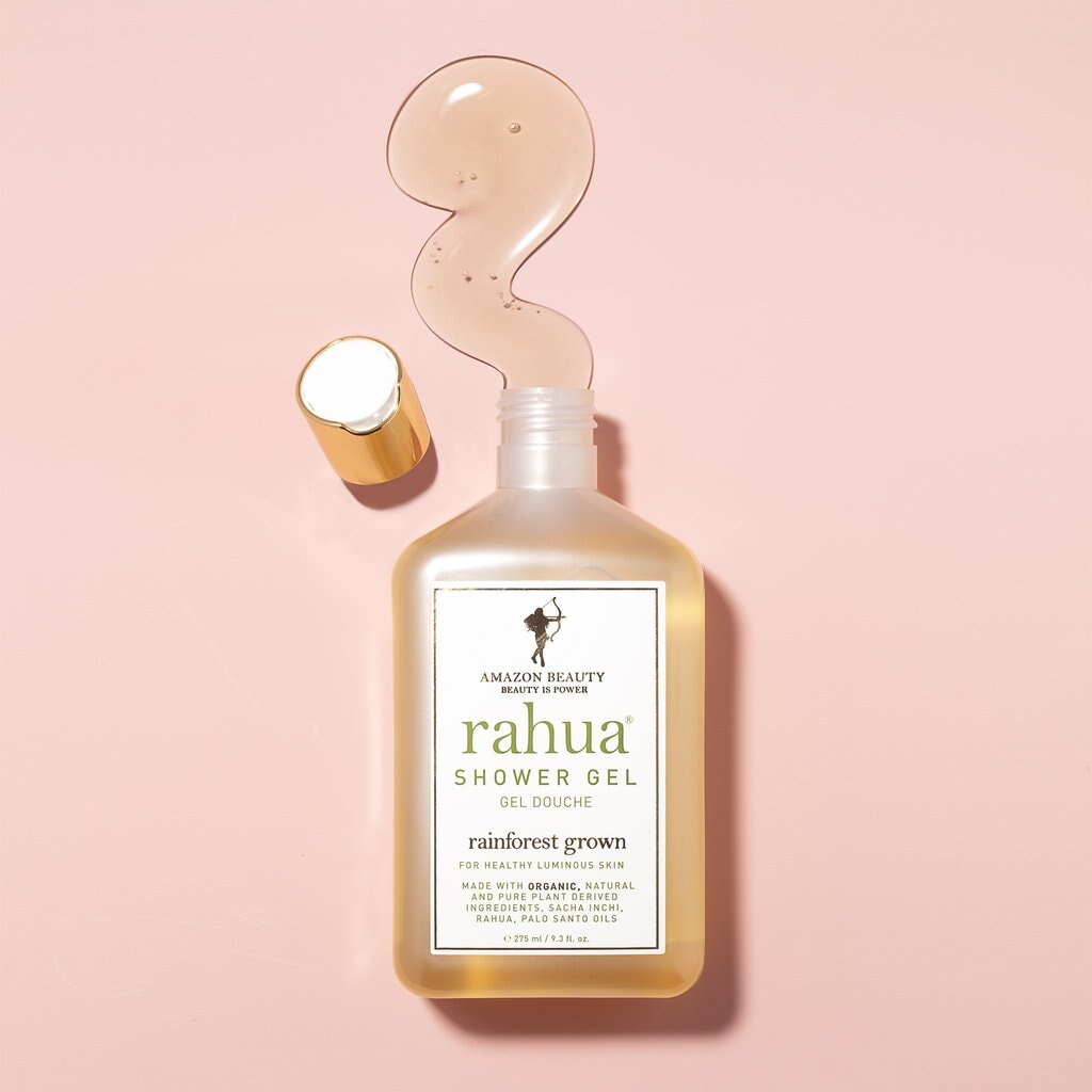Offene Rahua Shower Gel Flasche vor rosafarbenem Hintergrund mit Texturbeispiel.