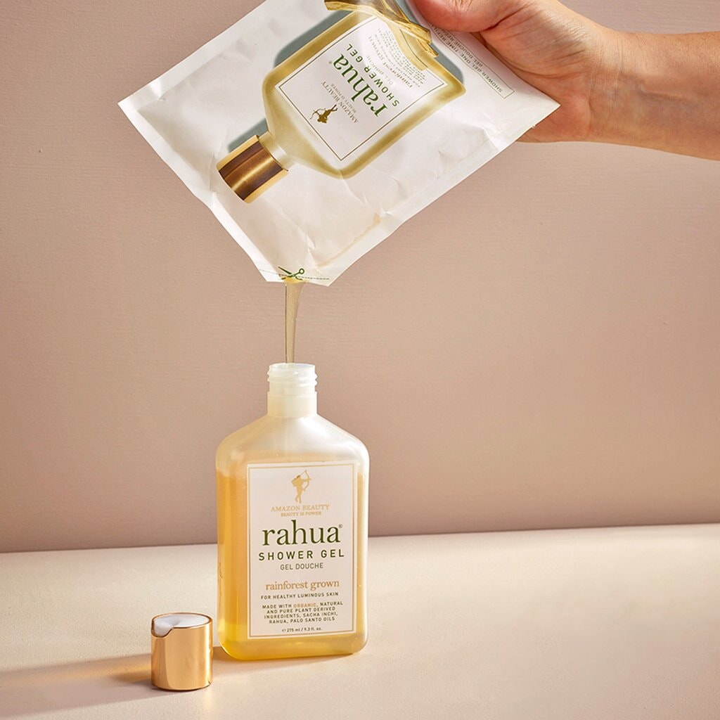 Hand hält Rahua Shower Gel Nachfüllbeutel und füllt die Originalflasche auf. North Glow