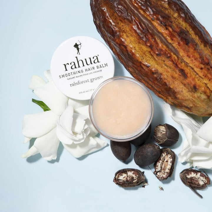 Offenes Rahua Smoothing Hair Balm Schraubglas aus der Vogelperspektive dedoriert mit Blütenblättern und Rahuanuss.