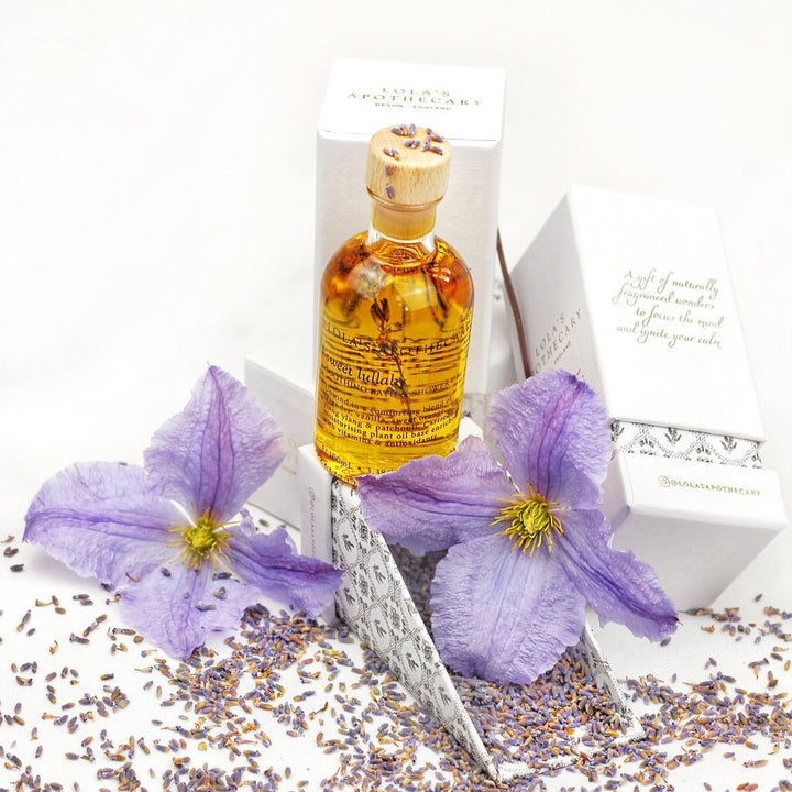 Lola's Apothecary Glasflasche mit Korken steht vor der Verpackung auf Lavendelblüten.