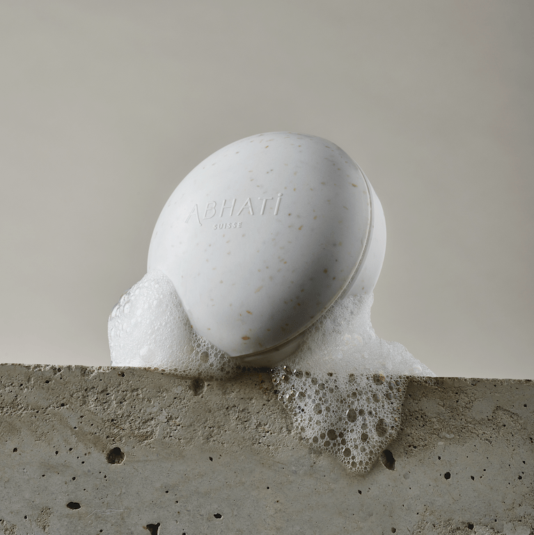 The Pebble Behälter von Abhati Suisse steht eingeschäumt auf einer Steinplatte.