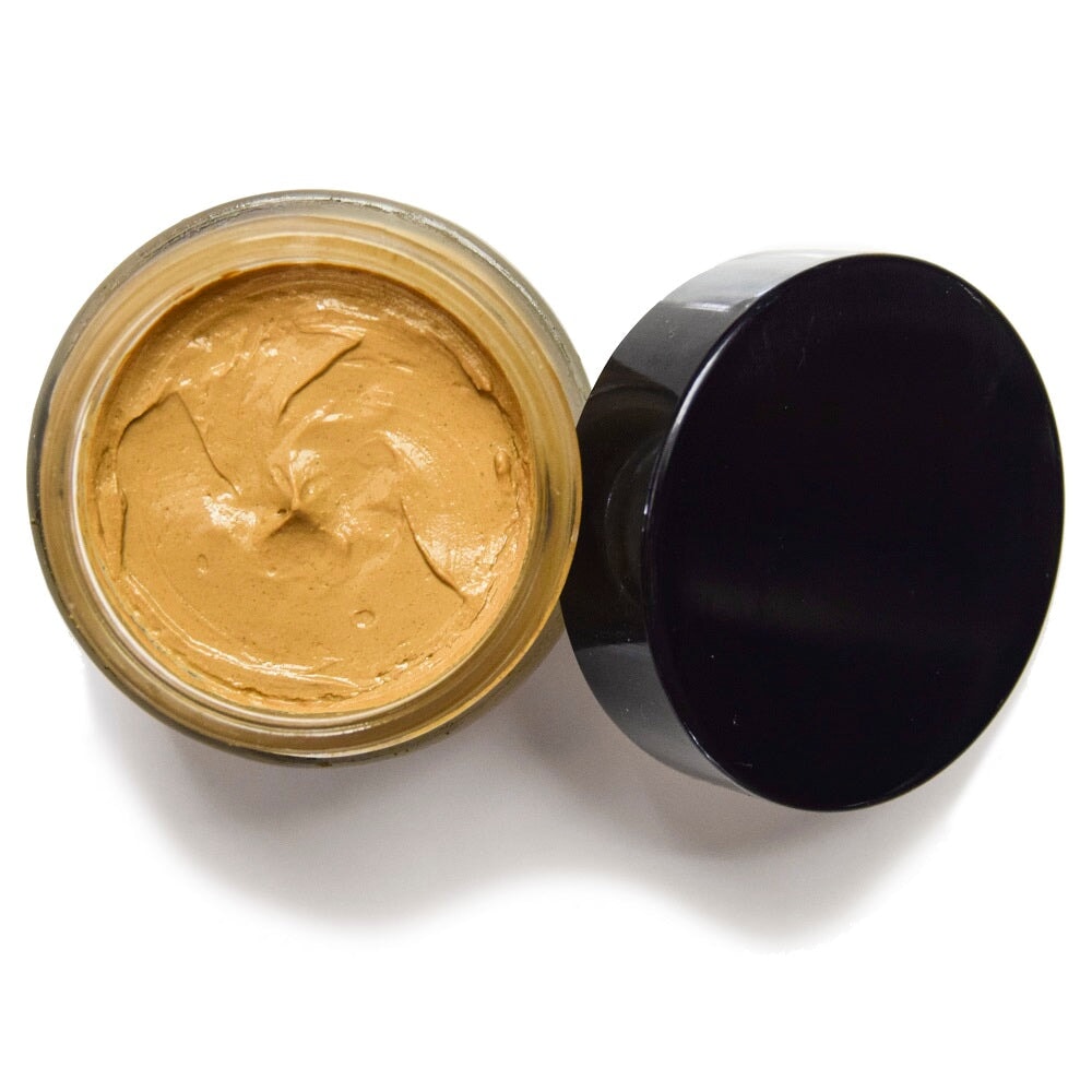 Offenes UMA Ultimate Brightening Face Mask Schraubglas mit angelehntem schwarzem Deckel aus der Vogelperspektive. North Glow