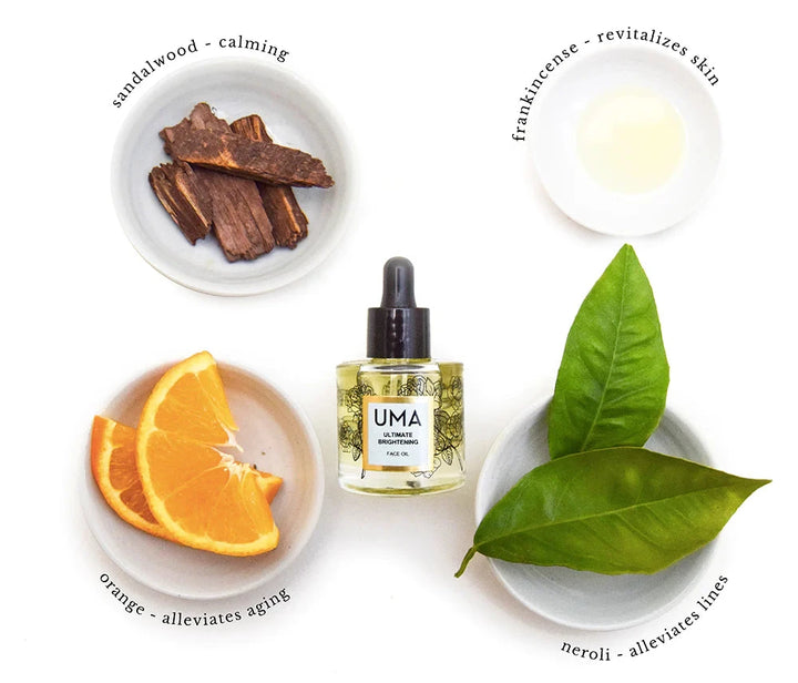 UMA Ultimate Brightening Face Oil Flasche liegt in der Mitte umringt von Schälchen mit den Zutaten Sandelholz, Frankincense, Neroliblättern und Orangenscheiben.