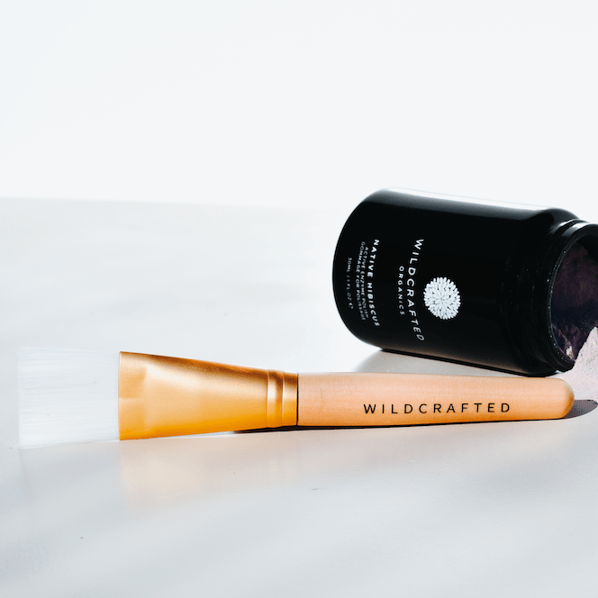 Wildcrafted Organics Vegan Masque Brush liegt neben einem schwarzem Tielge der Wildcrafted Organics Native Hibiscus Masque.