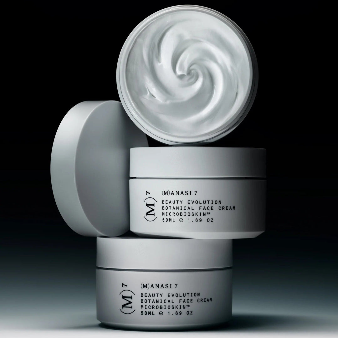 Open jar of Manasi 7 Botanical Face Cream Furora stands on 2 closed jars against a dark background.