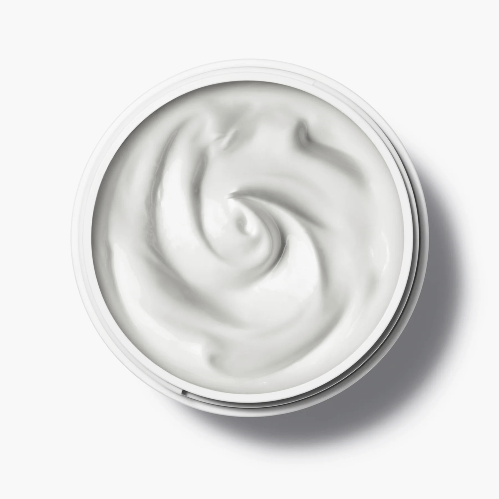 Open jar of Manasi 7 Botanical Face Cream Furora from a bird's eye view on a white background.