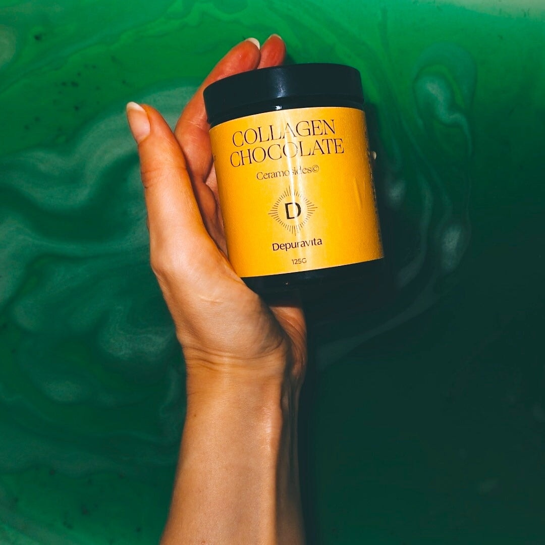 One hand holds Depuravita screw-top jar of Collagen Chocolates against a green background. North Glow