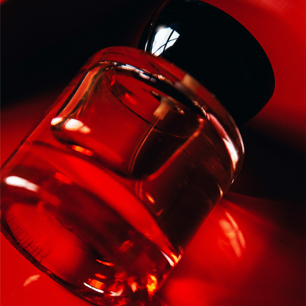 Vyrao Georgette glass bottle with black lid and reddish bottle against a red background.