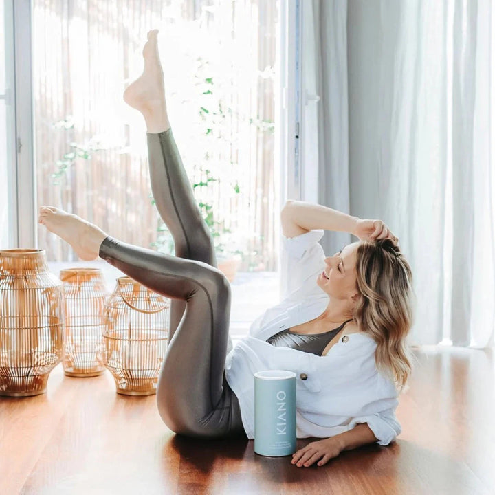 Woman half lying on the floor and stretching her legs in the air. Next to her is a can of Kiano Green Fuel.