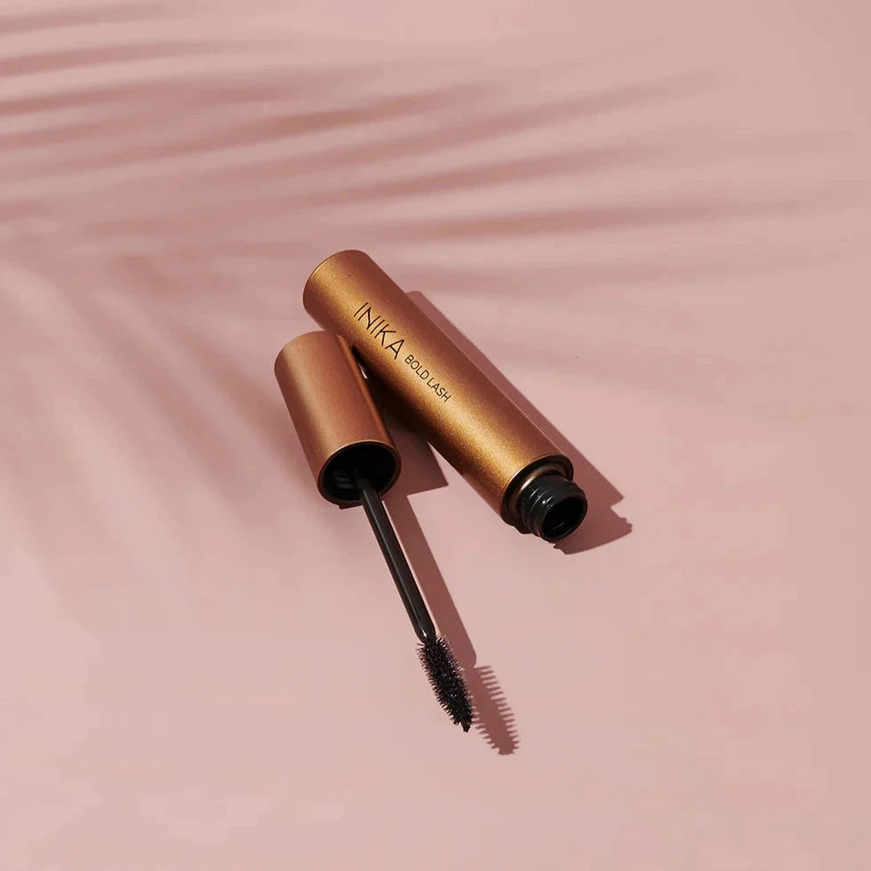 INIKA Mascara open and lying against a light background with a shadow of a palm leaf. North Glow