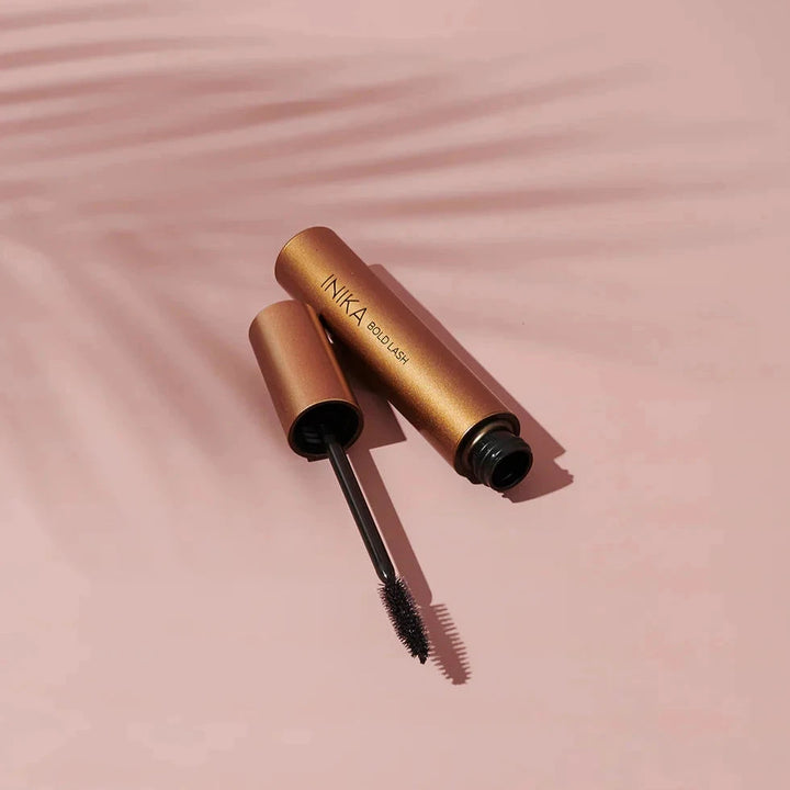 INIKA Mascara open and lying against a light background with a shadow of a palm leaf.