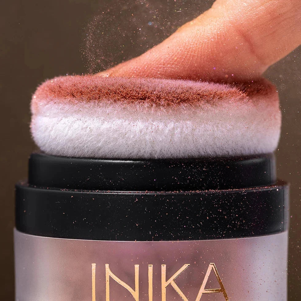 A finger presses on the Mineral Blush Puff Pot. North Glow