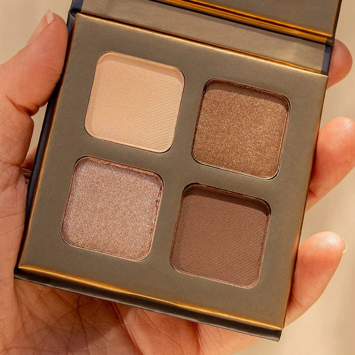 INIKA Organic Quad Eyeshadow Palette (wind) opened and held by one hand.