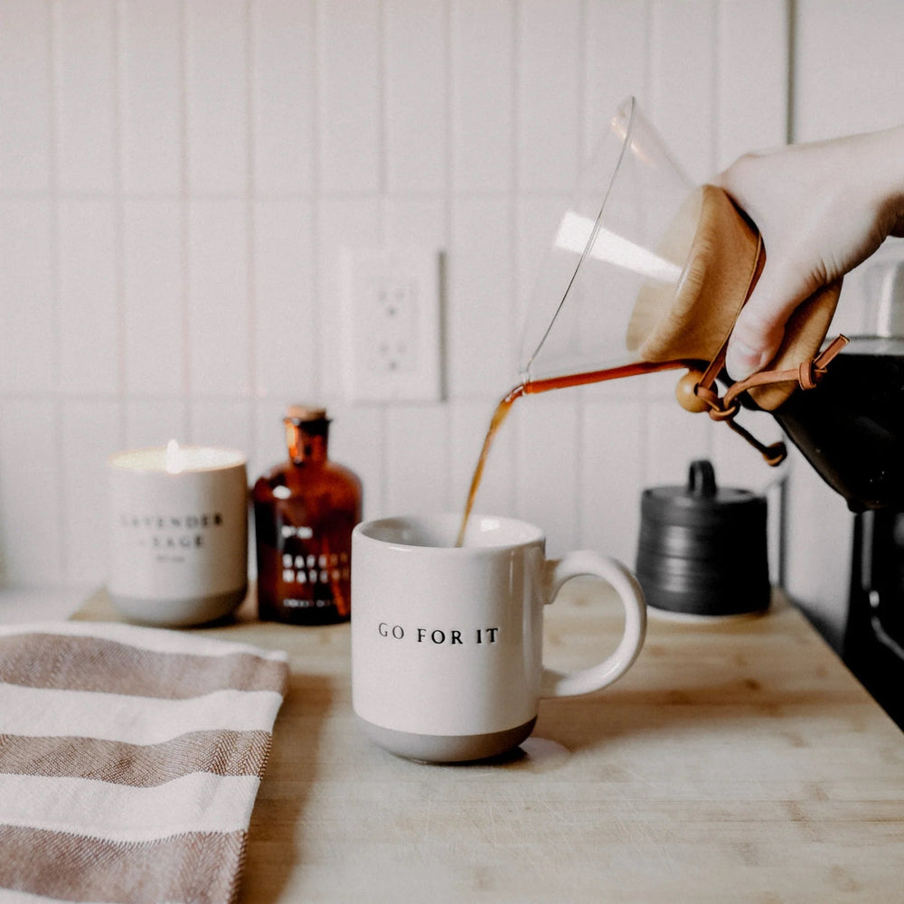 Aus einer Glaskaraffe wird Kaffee in die Kaffeetasse "Go for it" von Sweet Water Decor eingegossen.