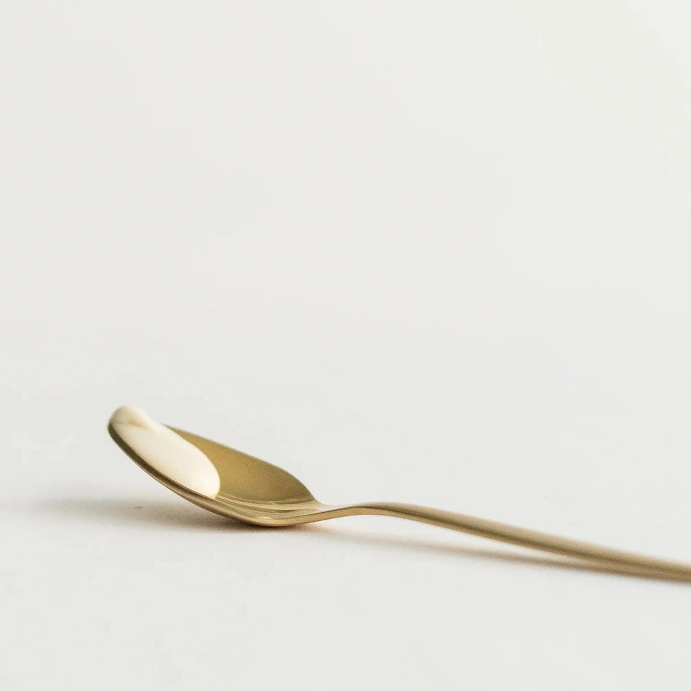 Golden spoon, lying with a small blob of MOISTURE + LIGHT cream from Dafna's.