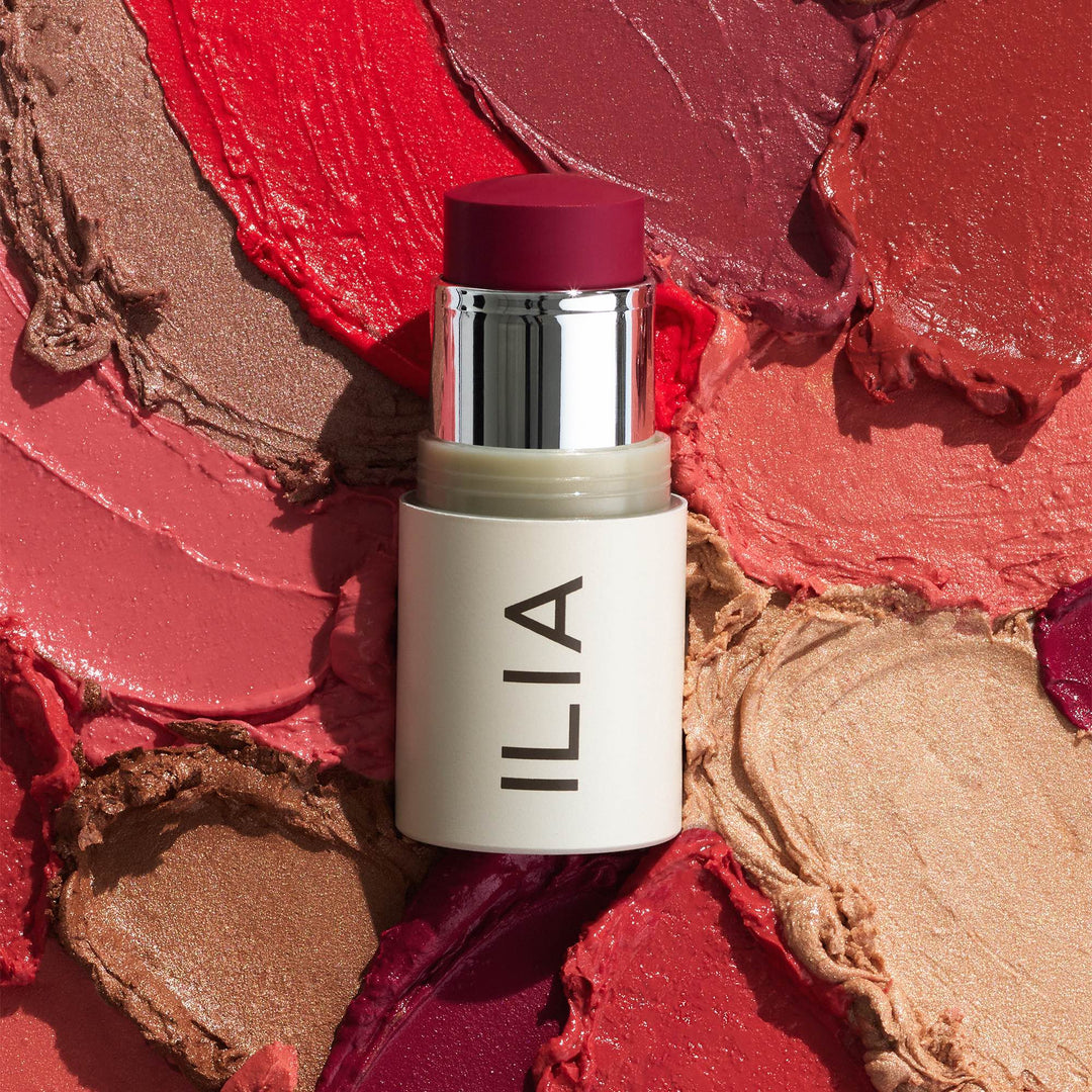 ILIA MultiStick A Fine Romance open in front of different color examples of the Multi-Sticks. North Glow