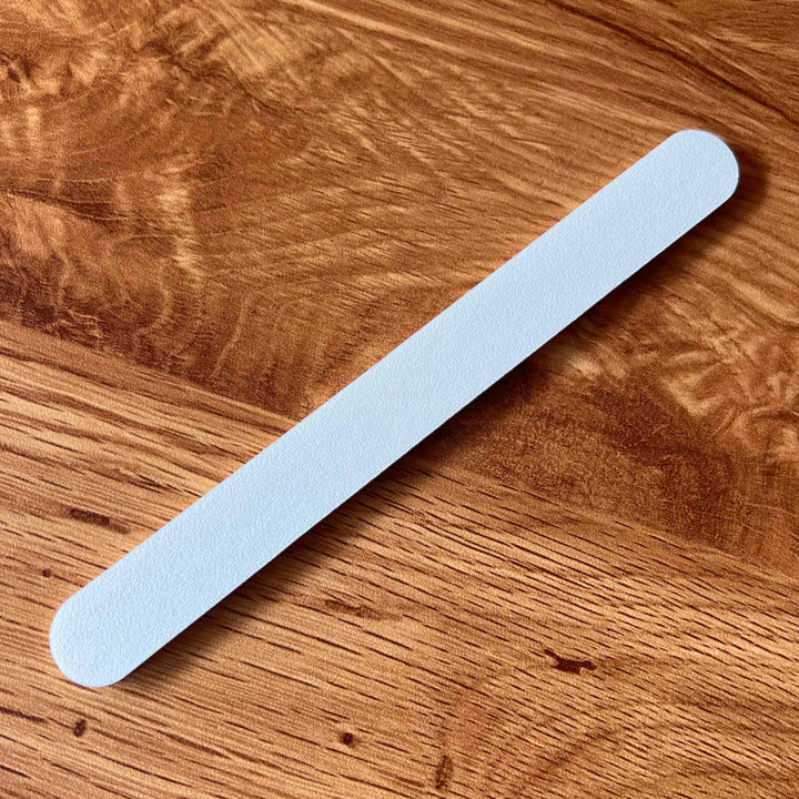 Nail file from Kure Bazaar white lies on wood.