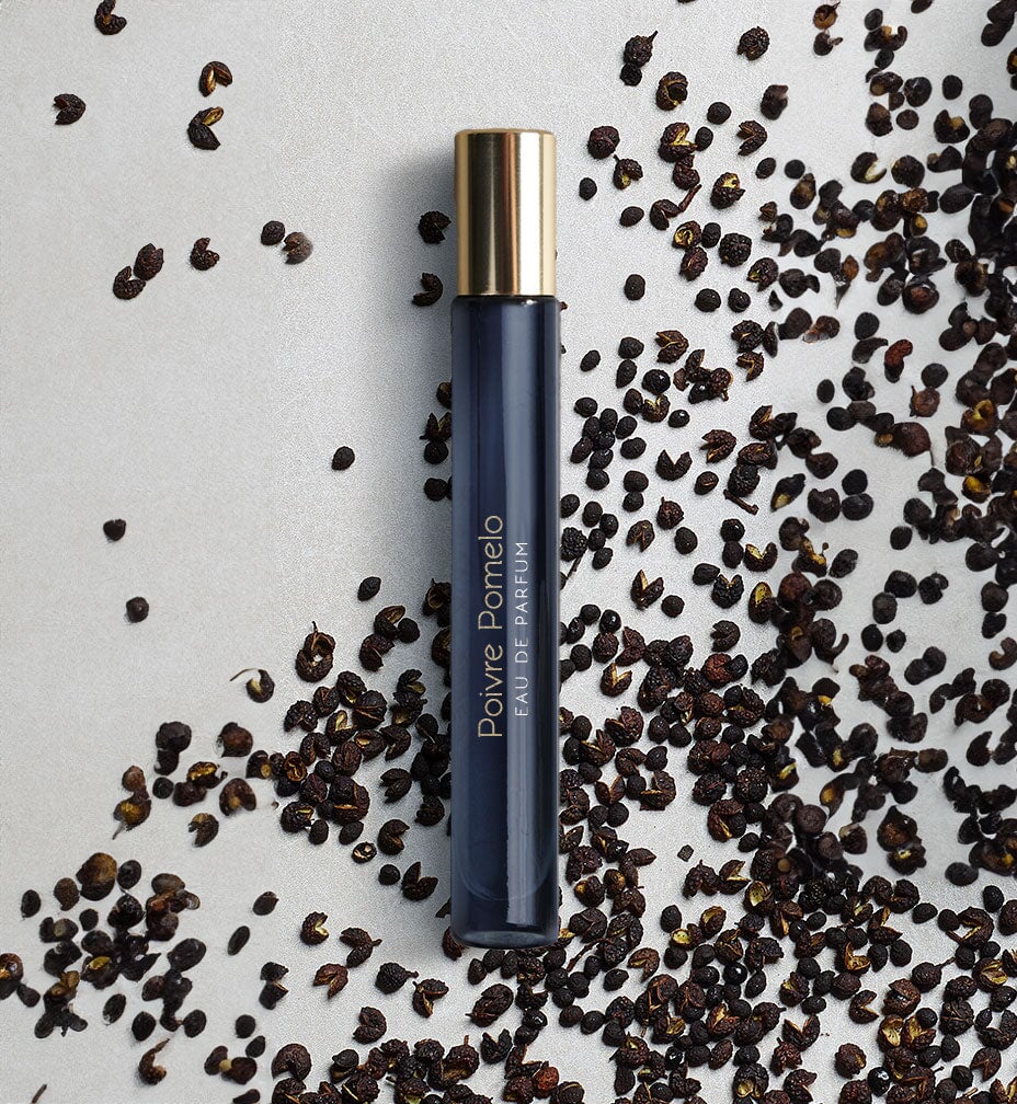Dark blue, narrow glass jar with golden lid surrounded by brown grains. North Glow