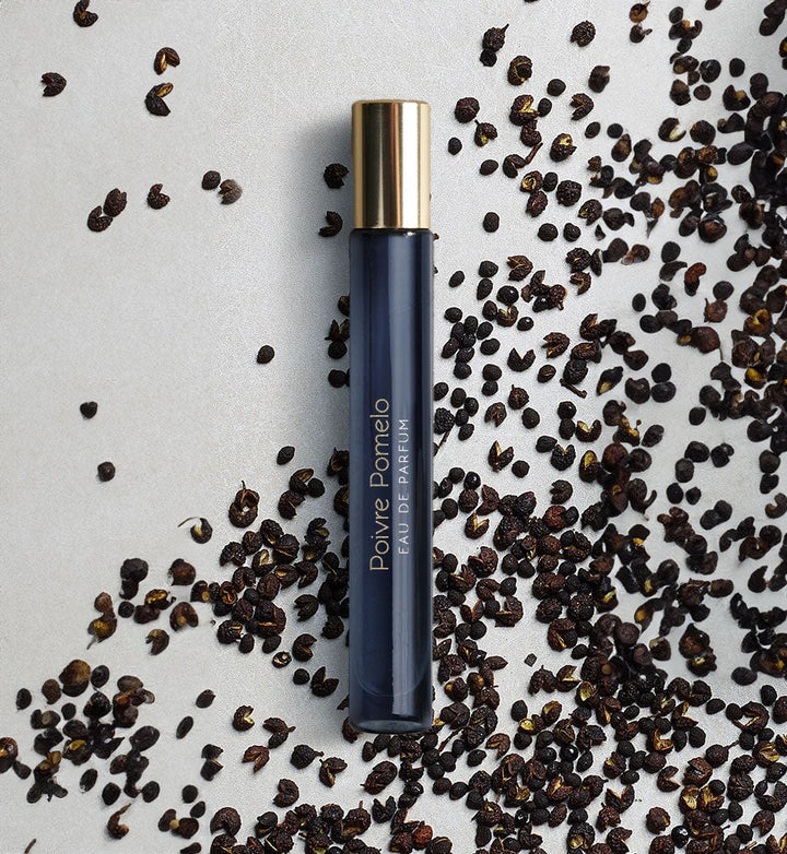 Dark blue, narrow glass jar with golden lid surrounded by brown grains.