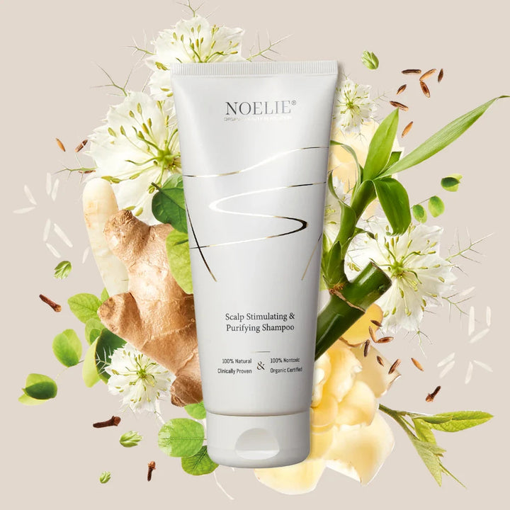 NOELIE Scalp Stimulating & Purifying Shampoo, im Hintergrund Blumen & Pflanzen.