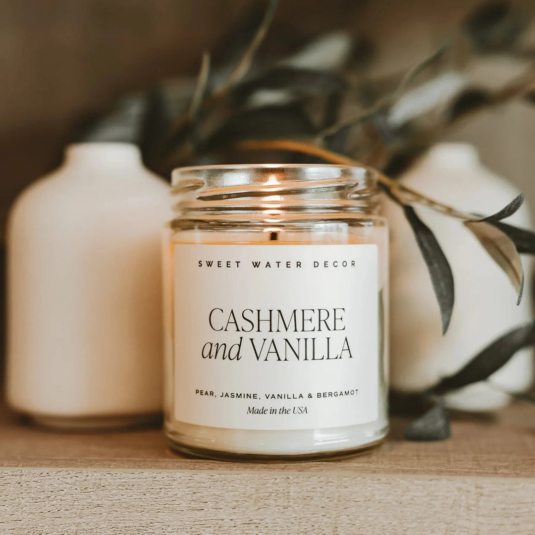 Brennende Sojawachskerze Cashmere and Vanilla steht vor Zweigen. North Glow