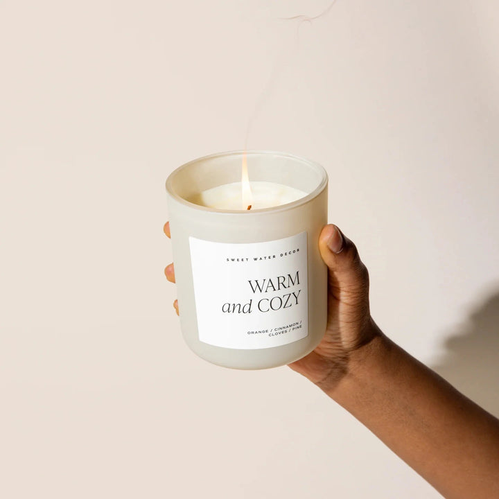 Cream-colored milk glass with candle is held in one hand.