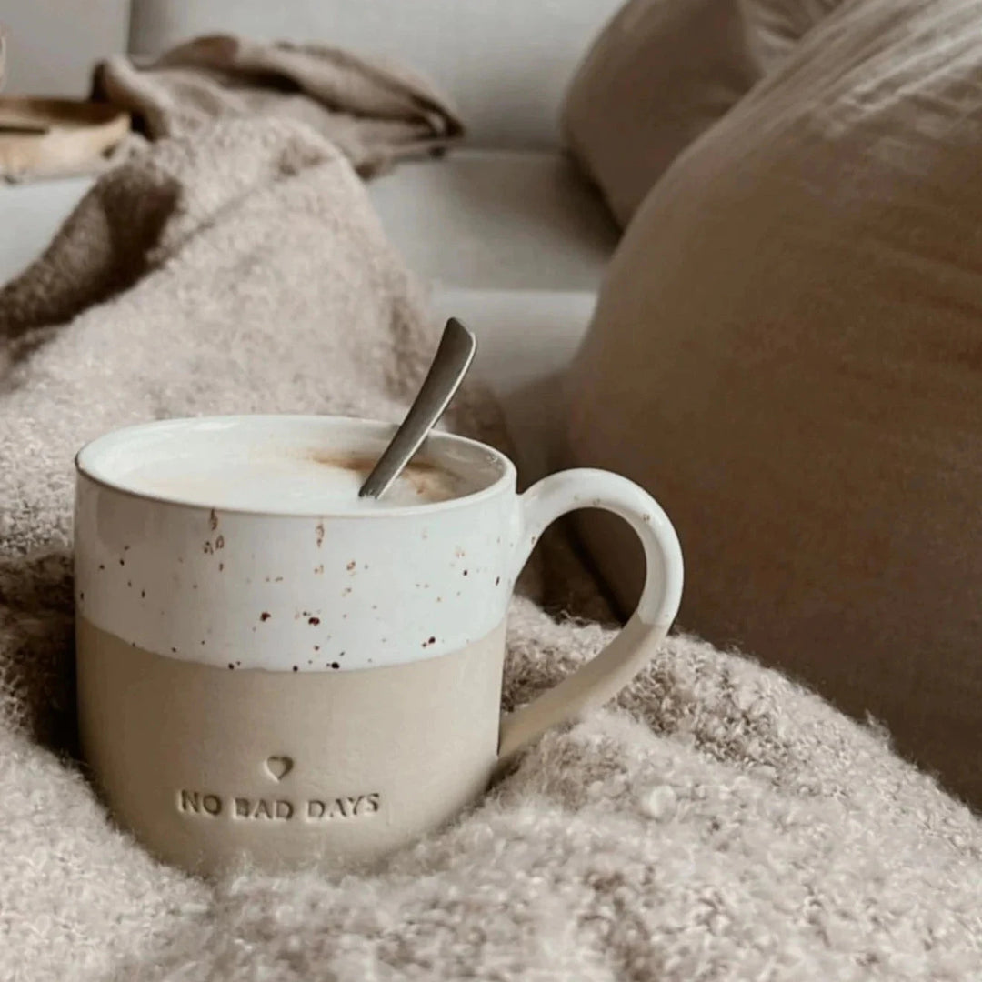 Mug with embossing "no bad days" by Eulenschnitt stands on a cream-colored wool blanket.