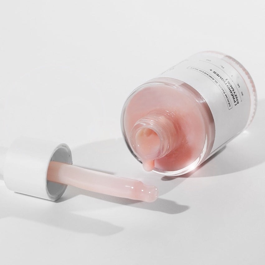 Glasflasche mit dem Serum von the smilist liegt auf hellem Untergrund, Serum tropft, daneben liegt die Pipette. North Glow