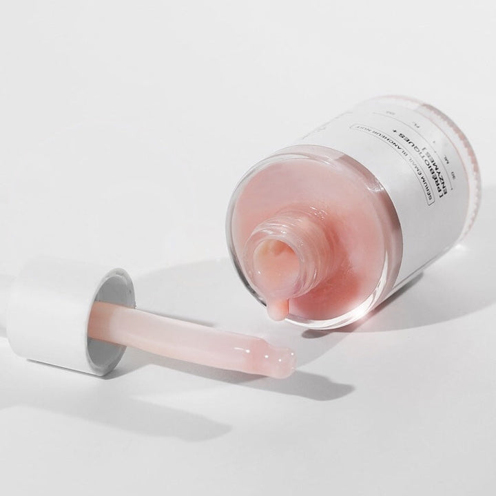 Glasflasche mit dem Serum von the smilist liegt auf hellem Untergrund, Serum tropft, daneben liegt die Pipette.