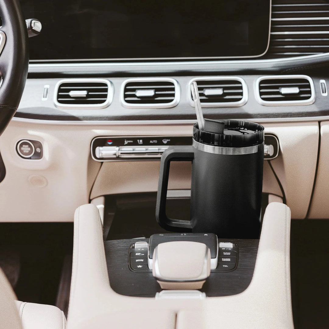 Schwarzer Tumbler / Thermobecher von Sweet Water Decor steht in der Mittelkonsole eines Autos. North Glow