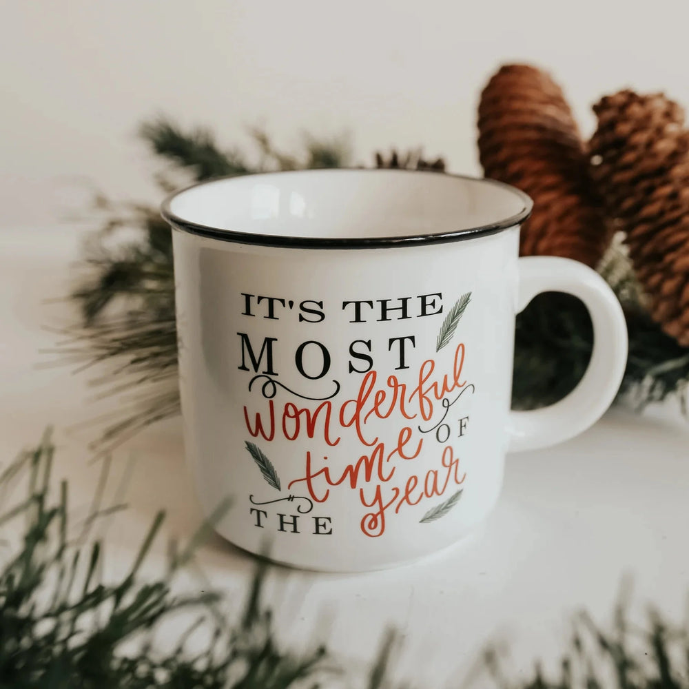 Sweet Water Decor Tasse Most Beautiful Time Of The Year steht zwischen Tannendeko und Tannenzapfen.