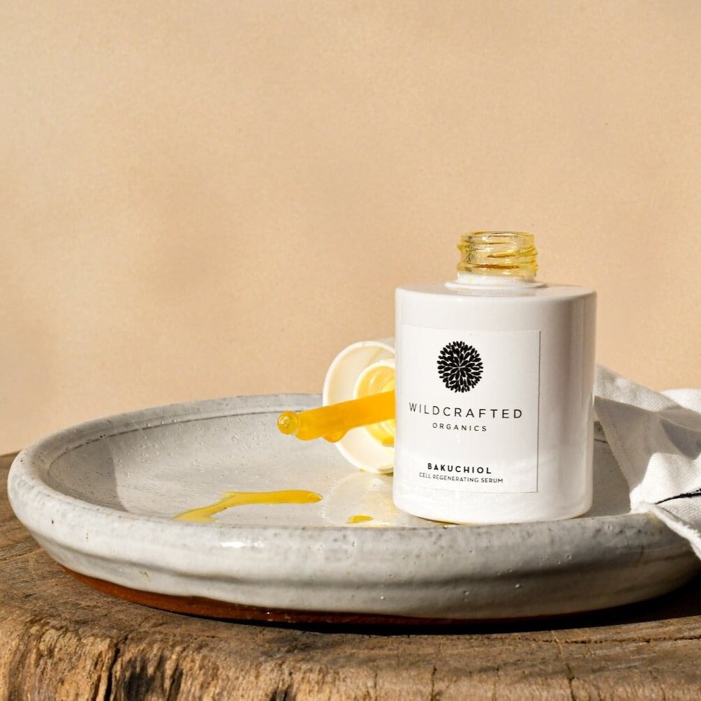 Wildcrafted Bakuchoil Cell Regenerating Serum Opened with Orange Texture on Light Plate