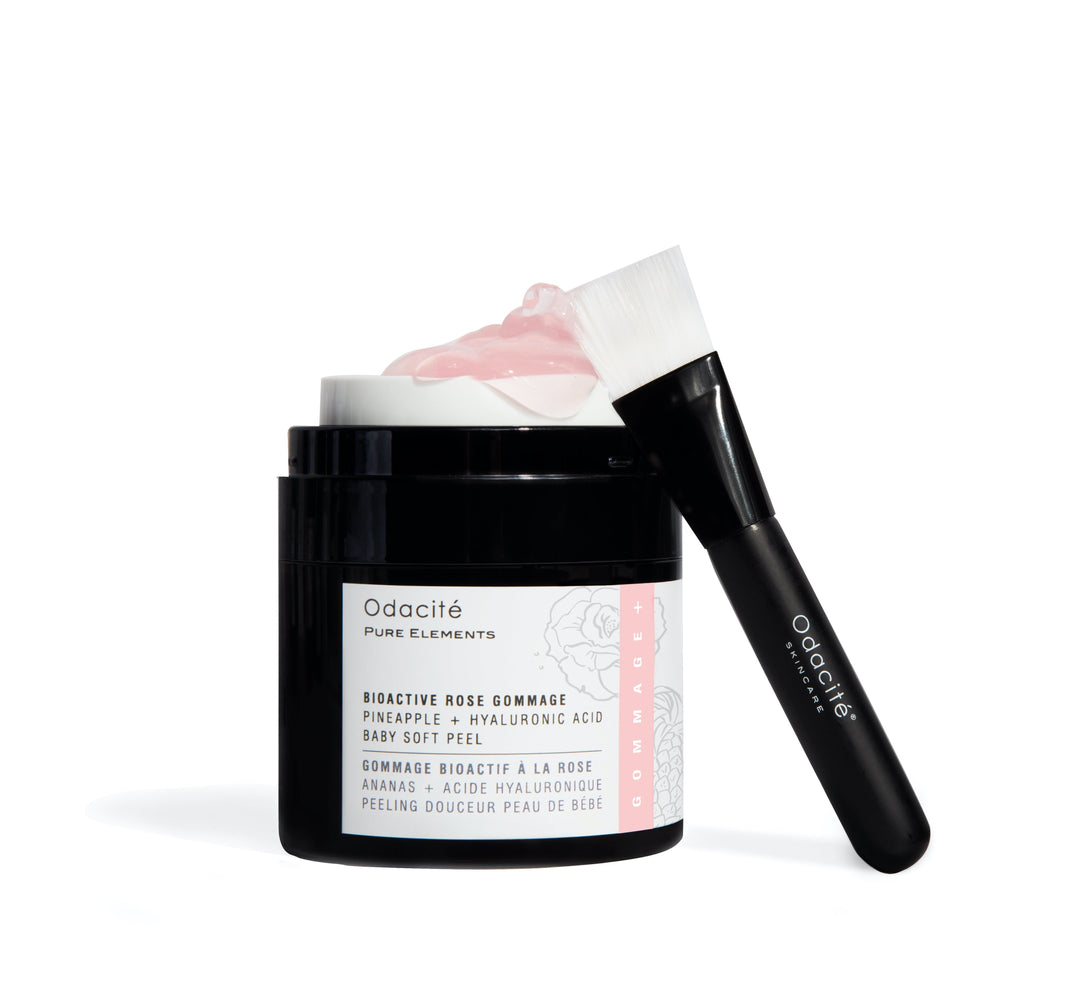 Open jar of Odacié Bioactive Rose Gommage, with brush leaning against a white background.