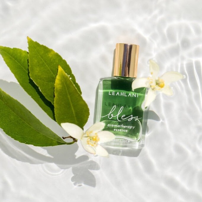 Leahlani Bless Aromatherapy Essence bottle with green leaves and white flowers in water