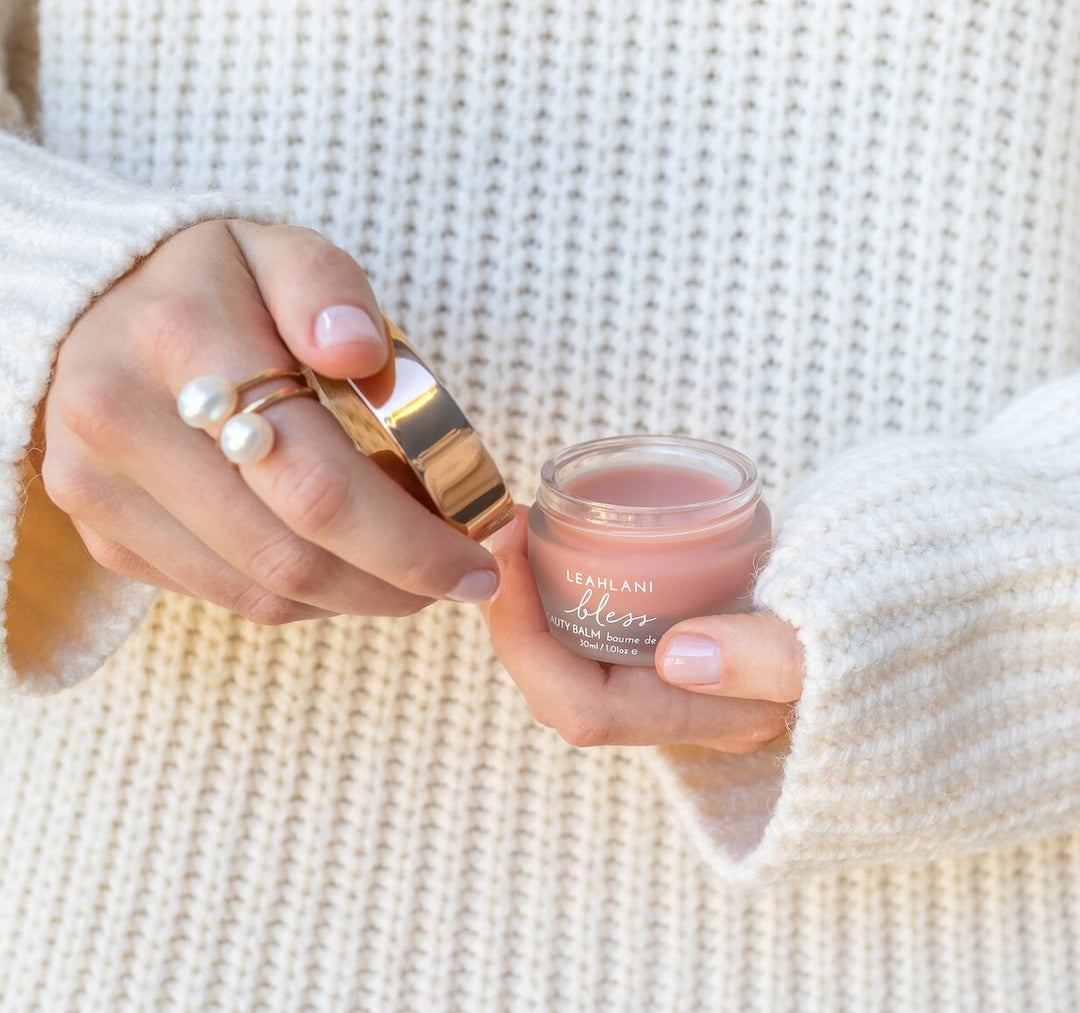 Detail of female model holding opened Leahlani Bless Beauty Balm jar North Glow