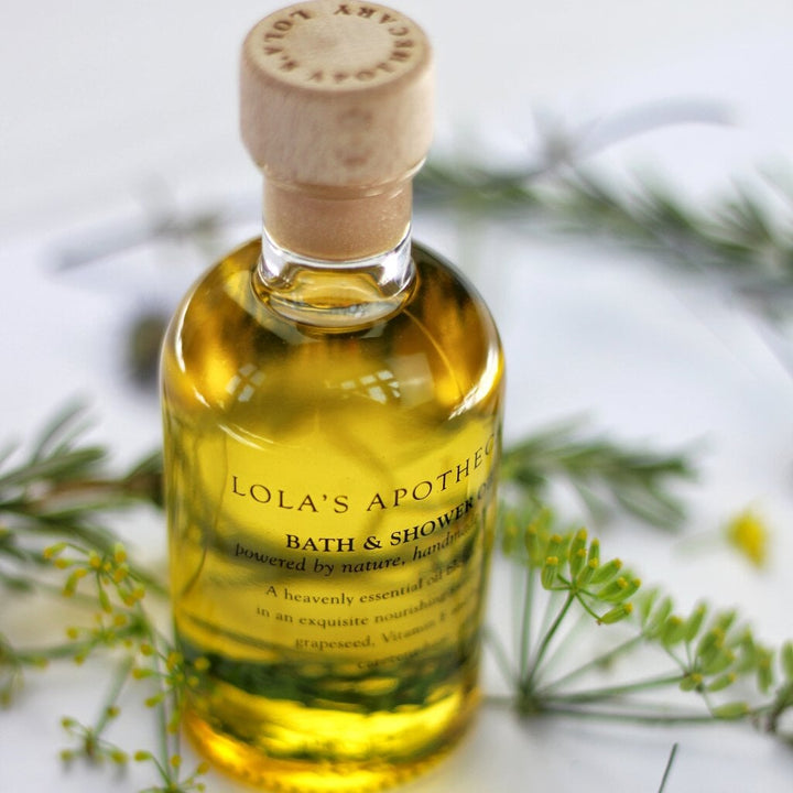 Lola's Apothecary Breath of clarity Bath & Shower Oil bottle against bright background with green plants