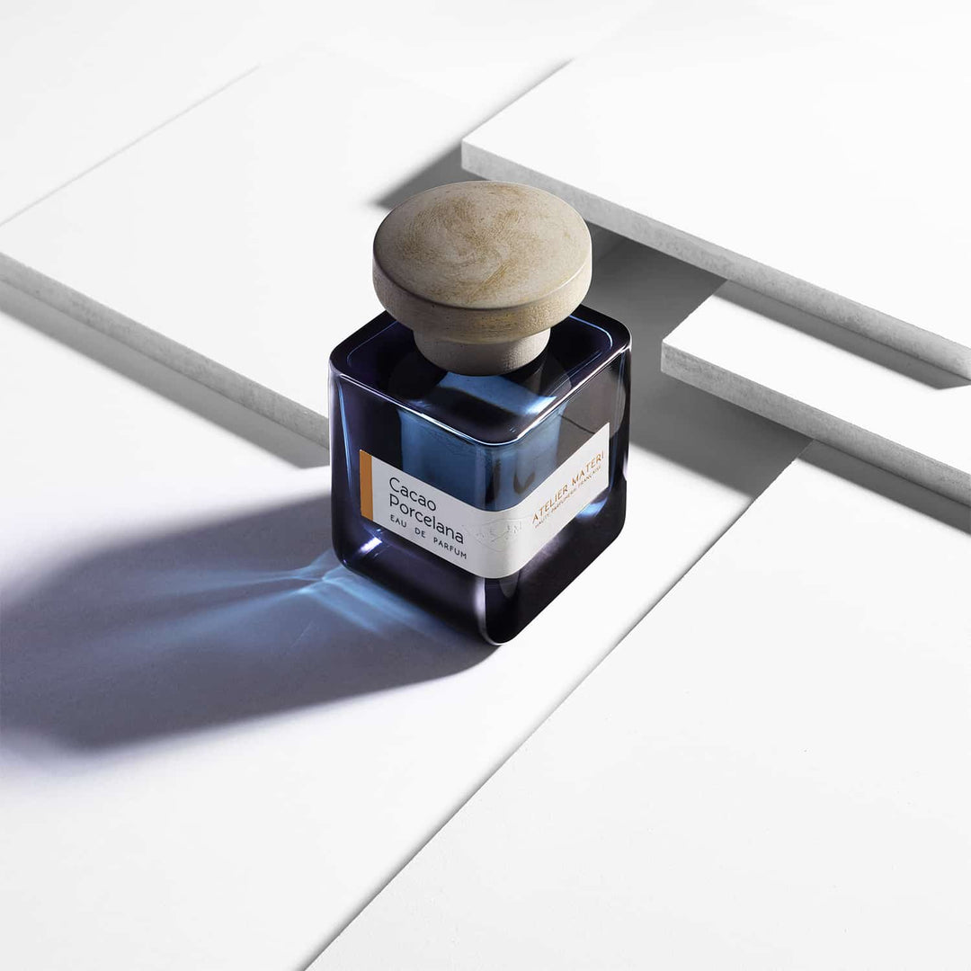 Dark blue glass bottle with green lid "Cacao Porcelana" by Atelier Materi stands on a white surface. North Glow