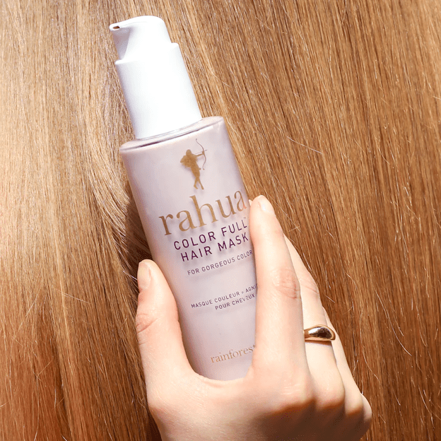 Rahua Color Full Hair Mask bottle against a purple background, lying on a bed of reddish, long hair.  North Glow